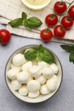 Lezzetli mozzarella peyniri topları, domates ve fesleğen açık gri masada, düz yatıyordu