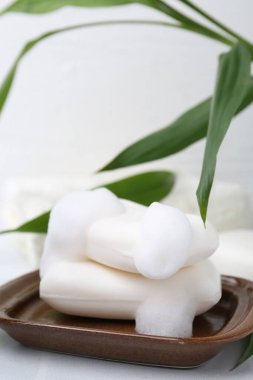 Beyaz masadaki köpüklü sabun çubukları, yakın plan. Metin için boşluk