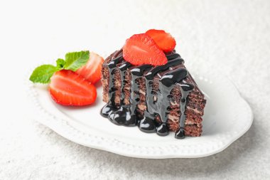 Bir parça çikolatalı kek, beyaz masada çilekli, yakın plan.