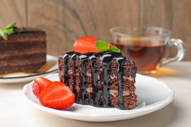 Çilek ve çay ile servis edilen bir parça çikolatalı kek, yakın plan.