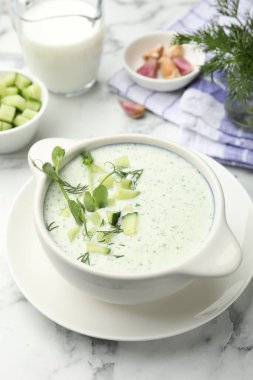 Dereotlu salatalık çorbası, mikro yeşiller ve beyaz mermer masa üzerindeki malzemeler, yakın plan.