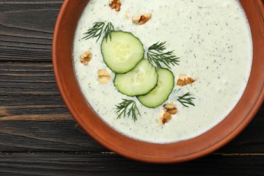 Ahşap masada dereotlu ve cevizli leziz salatalık çorbası.