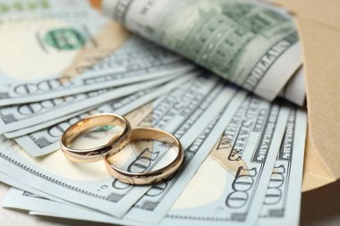 Masada iki altın alyans, bir dolarlık banknotlar ve zarf, yakın plan.