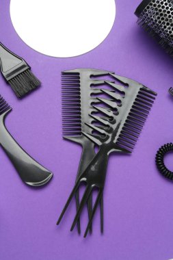 Mor arka planda farklı kuaför aletleri, düz yatış