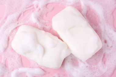 Pembe arka planda köpüklü sabun çubukları, düz yatış
