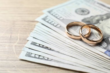 Altın alyanslar ve dolar banknotları ahşap masada, yakın plan.