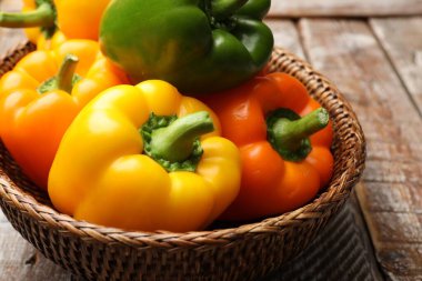 Taze renkli dolmalık biberler hasır sepetin içinde ahşap masanın üstünde, yakın plan.