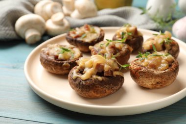 Eritilmiş peynirli lezzetli mantarlar ve açık mavi ahşap masada kekik, yakın plan.