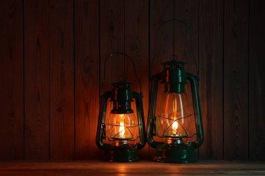 Ahşap masada iki eski gaz lambası.