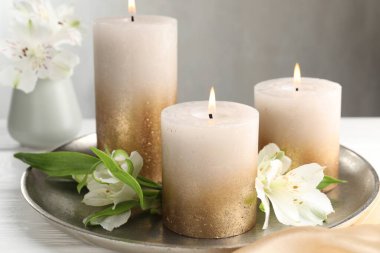 Beyaz masada yanan mumlar ve güzel çiçekler, yakın plan.