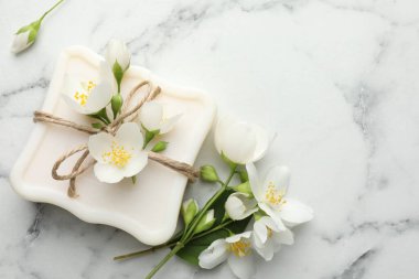 Sabun çubuğu ve yasemin çiçekleri beyaz mermer masada, düz yerde. Metin için boşluk