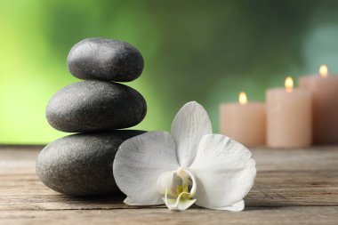 Kaplıca taşları ve orkide çiçeği ahşap masada, yakın plan.