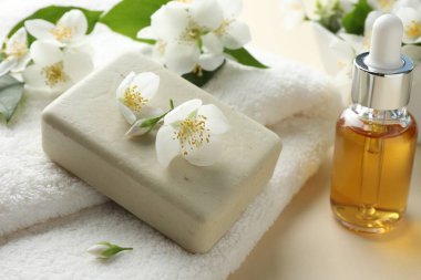 Sabun barı, havlu, esaslı yağ ve yasemin çiçekleri bej arka planda, yakın plan