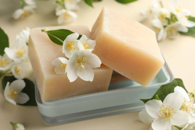 Bej arka planda sabun ve yasemin çiçekleri, yakın plan.