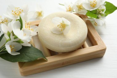 Sabun barı ve yasemin çiçekleri beyaz ahşap masada, yakın plan.