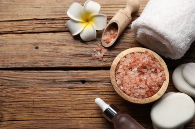 Spa taşları, kozmetik ürünleri ve çiçeklerle ahşap masa üzerinde düz bir kompozisyon vardı. Metin için boşluk