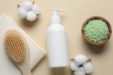 Düz kompozisyonda bej arka planda sıvı sabun ve pamuk çiçekleri vardı.