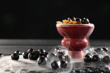 Frenk üzümlü nargile kasesi ve siyah masada duman, yakın plan. Metin için boşluk