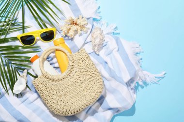 Plaj aksesuarları, deniz kabukları ve açık mavi arka planda palmiye yaprakları.