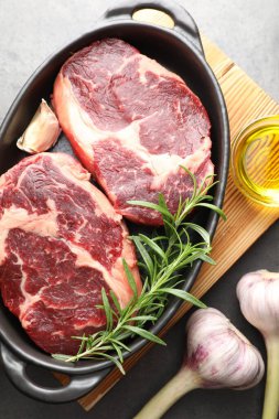 Baharatlı çiğ et parçaları fırın kabında ve gri masa üzerinde yağ, düz yatıyordu