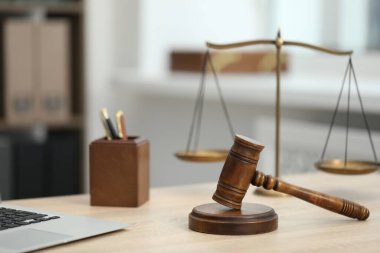 Dizüstü bilgisayar, yargıç tokmağı ve terazileri ofisteki ahşap masada.