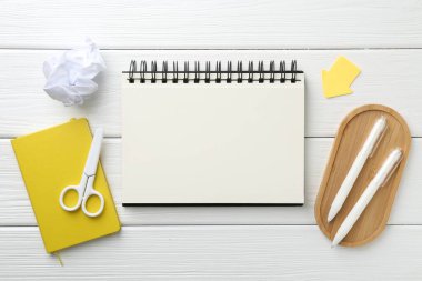 Düz kompozisyon ve beyaz ahşap masa üzerinde boş bir defter.