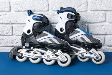 Beyaz tuğla duvarın yanındaki mavi masada bir çift paten.