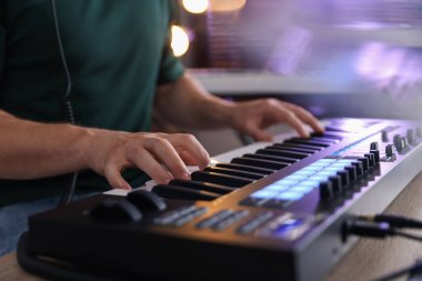İçerideki masada MIDI klavyesiyle çalışan adam, yakın plan.