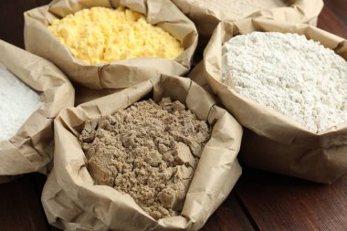 Tahta masadaki kağıt torbalarda farklı türde un, yakın plan.