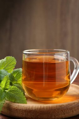 Cam bardakta Aromatik limon merhemi çayı ve ahşap masada taze yapraklar.