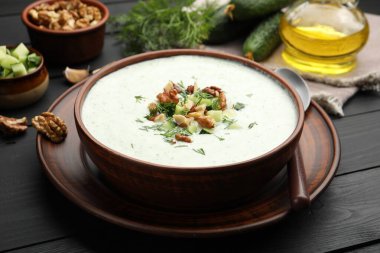 Siyah ahşap masada servis edilen dereotlu ve cevizli lezzetli salatalık çorbası.