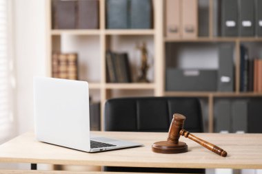 Hakimin tokmağı ve dizüstü bilgisayarı ofisteki ahşap masada.