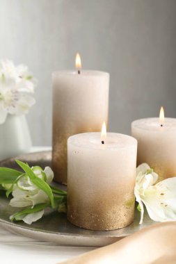 Beyaz masada yanan mumlar ve güzel çiçekler, yakın plan.