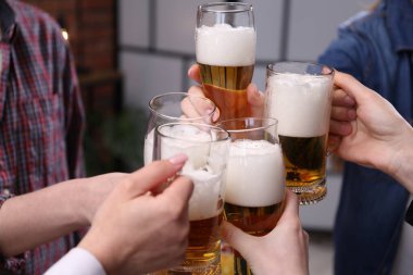 Arkadaşlar bira bardaklarını tokuşturur, yakın plan