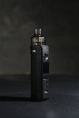 Koyu renkli masada gri arkaplana karşı elektronik sigara içme cihazı, yakın plan.
