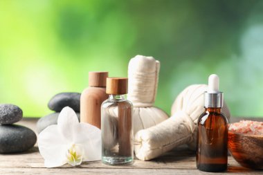 Kozmetik ürünleri, spa taşları ve ahşap masada bitkisel poşetler, yakın çekim.