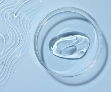 Petri kabında açık mavi arka planda kozmetik ürünü, üst görünüm