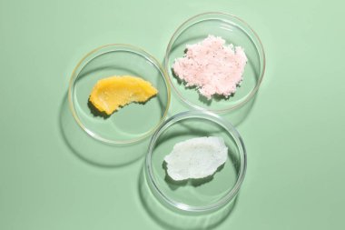 Petri kaplarında yeşil arka planda farklı kozmetik ürünleri var.