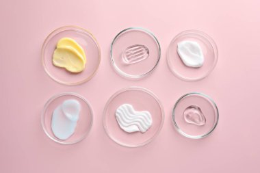 Petri kabında farklı kozmetik ürünleri pembe arka planda, düz yerde