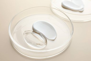 Petri kaplarında bej arka planda farklı kozmetik ürünleri, yakın plan