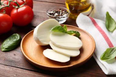 Lezzetli mozzarella, domates ve fesleğen ahşap masada, yakın plan.