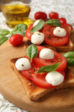 Peynirli lezzetli sandviçler, domatesler ve masa örtüsü üzerine fesleğen, yakın plan.