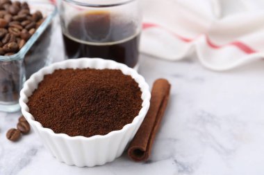 Kasedeki kahve tozu, tarçın çubuğu, fasulye ve içecek beyaz mermer masada, yakın plan. Metin için boşluk