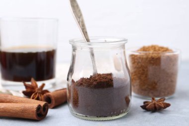 Kavanozda anlık kahve tozu ve gri masada hafif arka planda baharatlar, yakın plan.