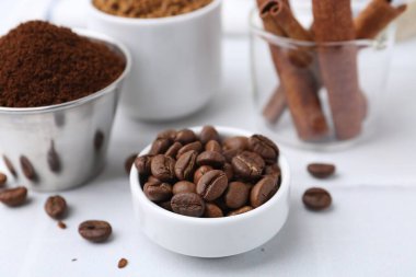 Kavrulmuş fasulye, farklı türde kahve ve tarçın çubukları ışık masasında, yakın plan.