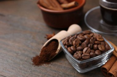 Kavrulmuş fasulye, hazır kahve tozu ve ahşap masada tarçın çubukları, yakın plan. Metin için boşluk