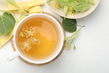 Taze ıhlamur çayı fincanda ve beyaz ahşap masada çiçekler düz yerde. Metin için boşluk