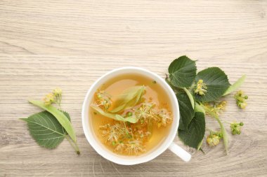 Taze ıhlamur çayı fincanda, çiçekler ahşap masada, düz yerde. Metin için boşluk