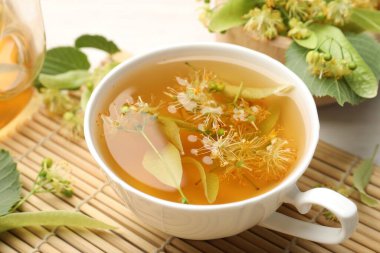 Taze ıhlamur çayı, çaydanlık ve çiçekler beyaz masada, yakın plan.