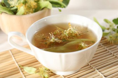 Fincanda taze ıhlamur çayı ve masada çiçekler, yakın plan.